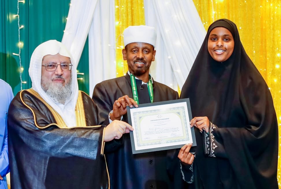 A student receiving her certificate alongside two teachers