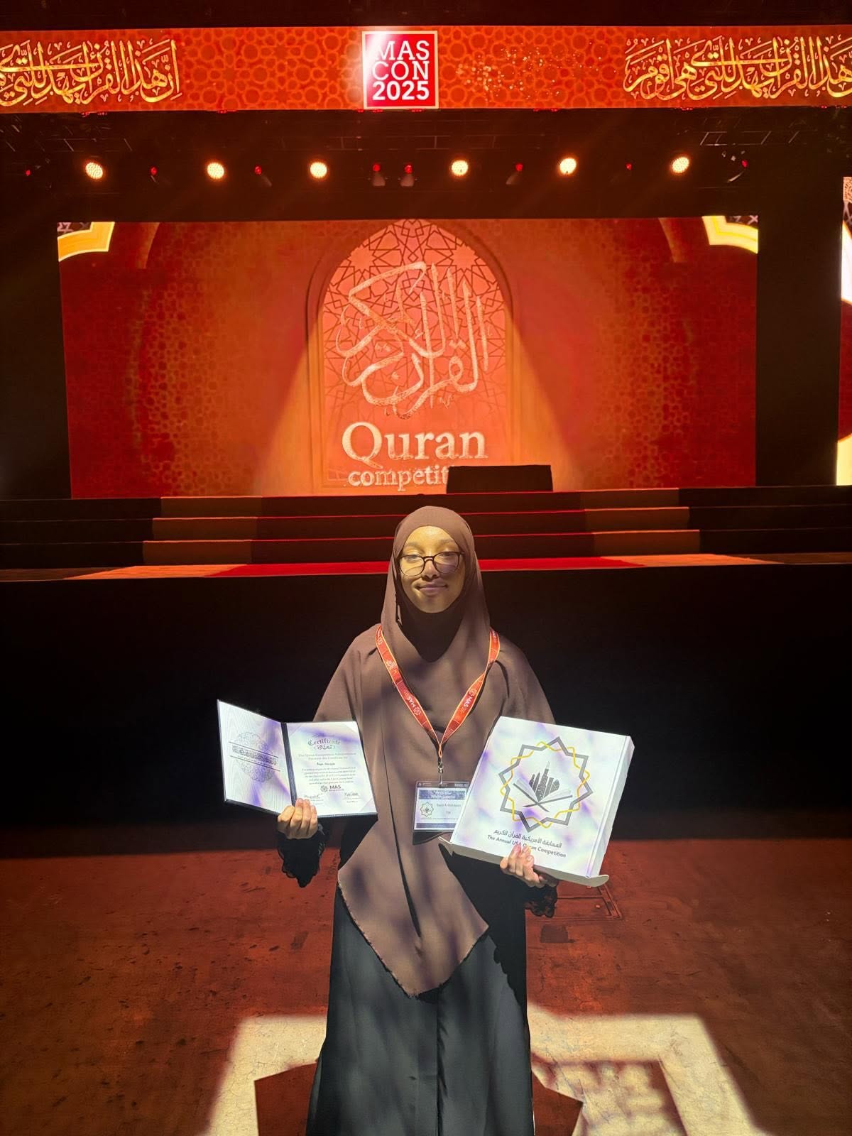A student holding her awards at the MAS-CON 2025 Qur'an Competition