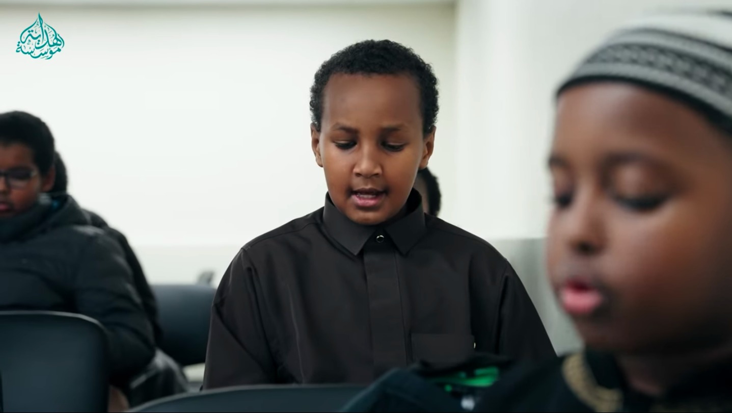 A Hidayah Institute student in a black thobe reading the Qur'an with focus and care
